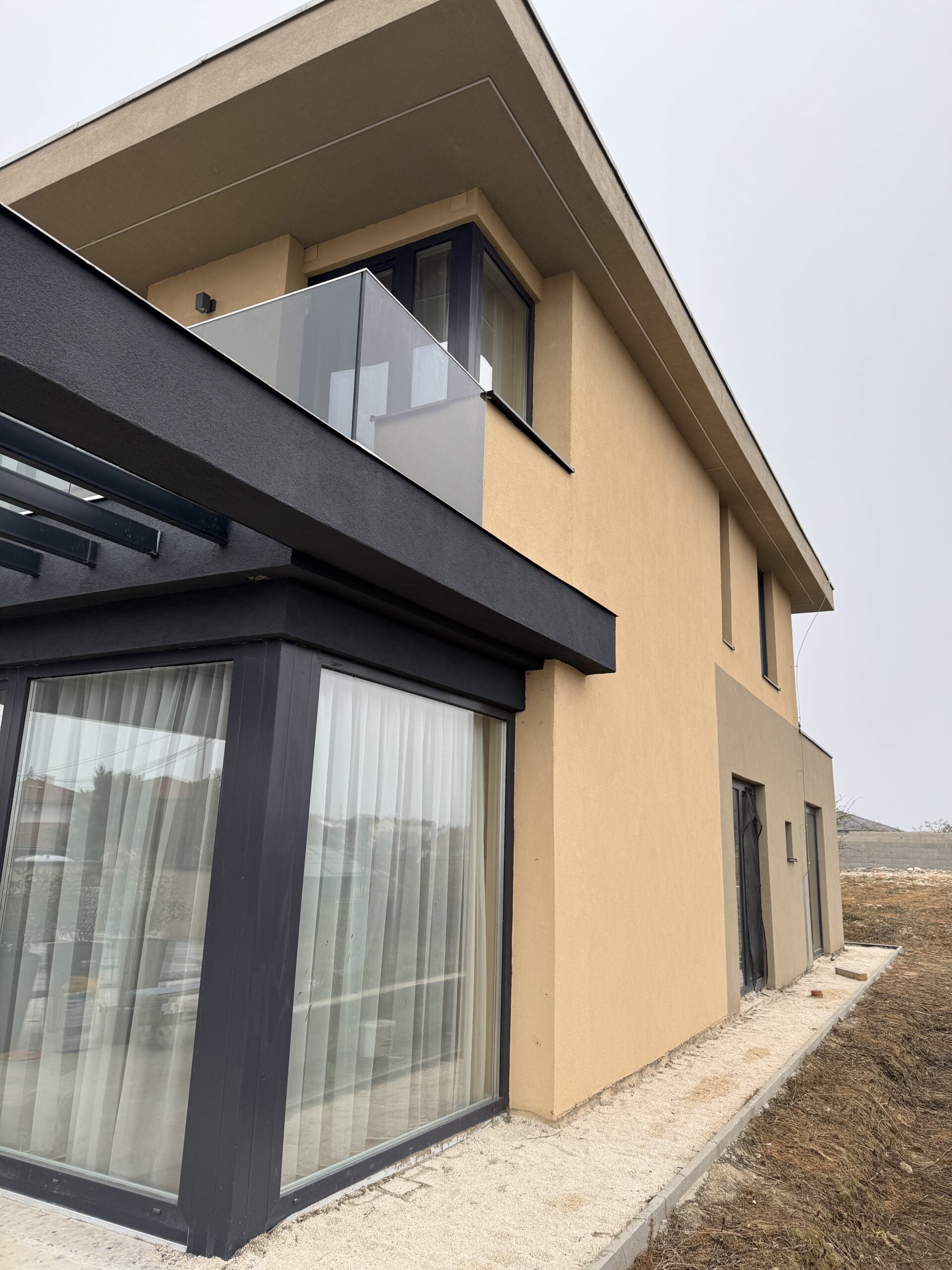 Modern megjelenésű új házak közé tartozó kétszintes ház nagy üvegfelületekkel és letisztult homlokzattal